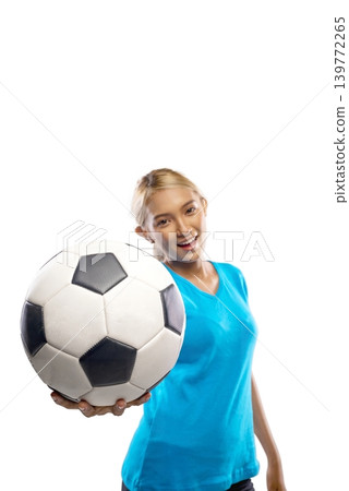 A beautiful young Indonesian southeast asian woman with blonde hair, wearing a blue t-shirt, poses while holding a classic black and white soccer ball near her face against a plain white background A beautiful young Indonesian southeast asian woman with blonde hair, wearing a blue t-shirt, poses while holding a classic black and white soccer ball near her face against a plain white background 139772265