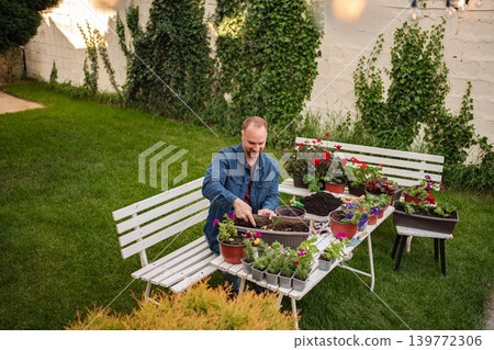 Gardener nurturing vibrant blooms in a serene backyard Gardener nurturing vibrant blooms in a serene backyard 139772306