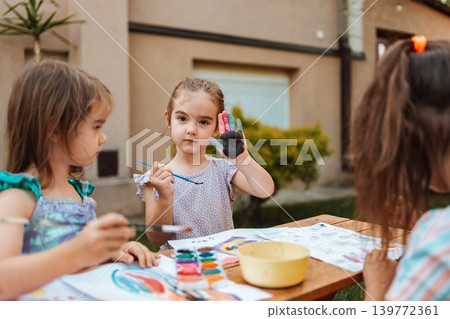 Little girls painting with watercolors in the backyard showing painted hands Little girls painting with watercolors in the backyard showing painted hands 139772361
