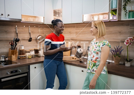Friends sharing a coffee moment in a cozy kitchen setting Friends sharing a coffee moment in a cozy kitchen setting 139772377