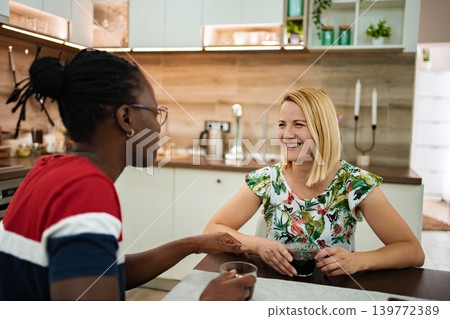 Friends enjoying conversation and coffee in a cozy kitchen setting Friends enjoying conversation and coffee in a cozy kitchen setting 139772389
