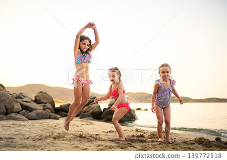 Happy young girls jumping and playing on beach vacation Happy young girls jumping and playing on beach vacation 139772518