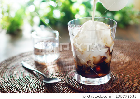 Summer iced café au lait - pour milk into iced coffee Summer iced café au lait - pour milk into iced coffee 139772535