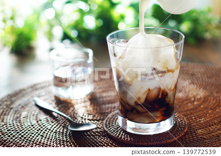 Summer iced café au lait - pour milk into iced coffee Summer iced café au lait - pour milk into iced coffee 139772539