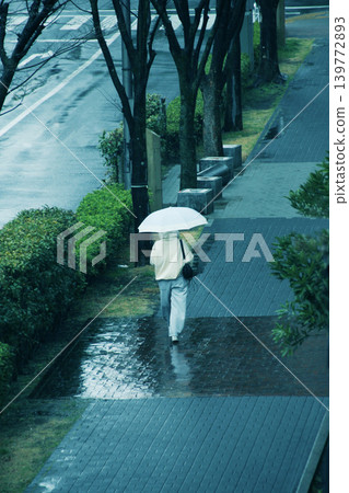 On a rainy morning, a group of women with matching umbrellas walk towards the train station. On a rainy morning, a group of women with matching umbrellas walk towards the train station. 139772893
