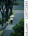 在一個下雨的早晨，一位撐著粉紅色雨傘的女士走向車站。 139772895