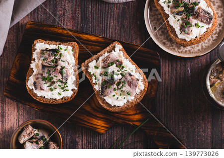 Delicious sandwiches on rye bread with ricotta, sardines and onions on a board top view 139773026
