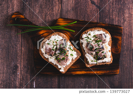 Close up of sandwiches on rye bread with ricotta, sardines and onions on a board top view 139773027
