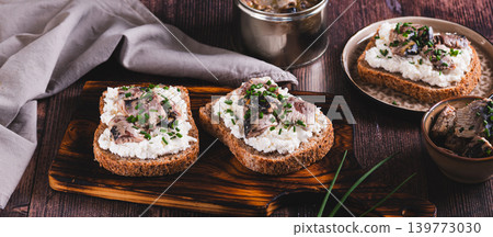 Delicious sandwiches on rye bread with ricotta, sardines and onions on a board web banner 139773030