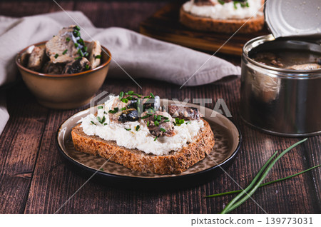 Open sandwiches with ricotta, sardines and chives on a plate on the table 139773031