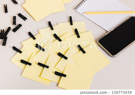 A pile of identical notepads, a smartphone, a notebook, and a pencil on the table A pile of identical notepads, a smartphone, a notebook, and a pencil on the table 139773039