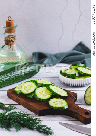 Fresh sliced crispy cucumbers on a cutting board on the table vertical view Fresh sliced crispy cucumbers on a cutting board on the table vertical view 139773155