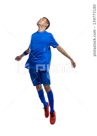 Full length of a Indonesian southeast asian soccer player in a blue uniform and red boots jumping mid-air while looking up, isolated on a white background 139773180