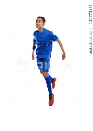 Full length of a Indonesian southeast asian soccer player in a blue uniform and red boots jumping mid-air while looking up, isolated on a white background 139773181