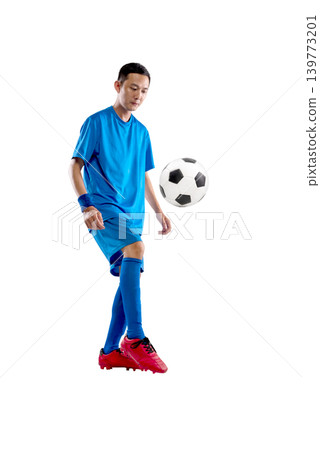 Full length portrait of a young Indonesian southeast asian man in a blue uniform kicking a soccer ball, isolated against a white background Full length portrait of a young Indonesian southeast asian man in a blue uniform kicking a soccer ball, isolated against a white background 139773201