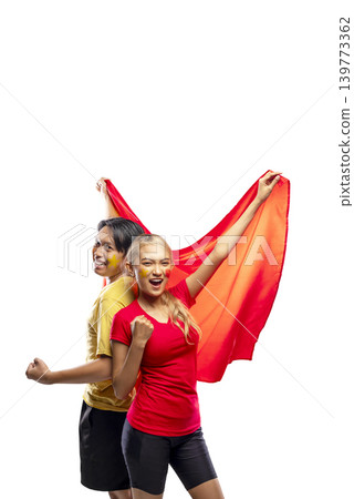 Two young Indonesian southeast asian enthusiastic fans, a man and a woman, cheering for their team with a red flag and face paint, celebrating victory isolated on a white background 139773362