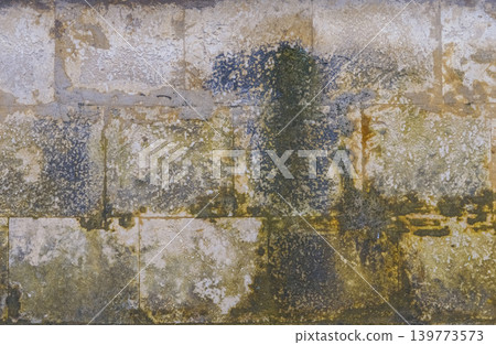 Weathered stone wall with moss. Old aged cement structure showcasing moss growth and stained patches Weathered stone wall with moss. Old aged cement structure showcasing moss growth and stained patches 139773573