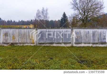Stone fence landscape. Solid concrete boundary separating peaceful natural area from open countryside Stone fence landscape. Solid concrete boundary separating peaceful natural area from open countryside 139773599