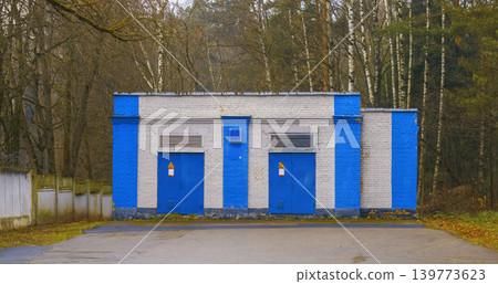 Abandoned industrial shelter. Remnants of deserted utility structure surrounded by trees and fading paint Abandoned industrial shelter. Remnants of deserted utility structure surrounded by trees and fading paint 139773623