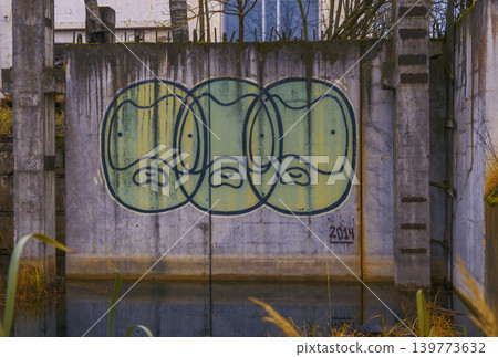 Urban art decay. Decayed concrete sculpture featuring stylized faces and mosscovered columns Urban art decay. Decayed concrete sculpture featuring stylized faces and mosscovered columns 139773632
