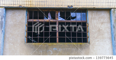 Dilapidated urban scene. Derelict building featuring shattered panes and hanging deteriorated fabric 139773645