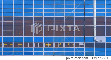 Sleek office tower with reflections. Contemporary structure featuring illuminated windows and grid design 139773661