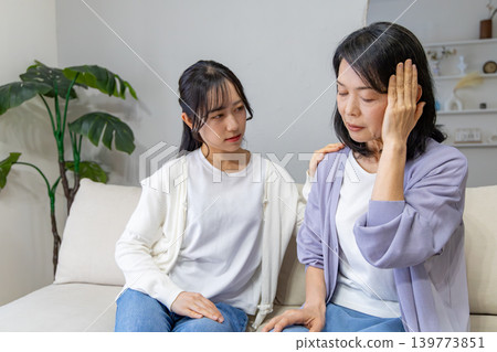 A mother holding her head and her worried daughter. 139773851