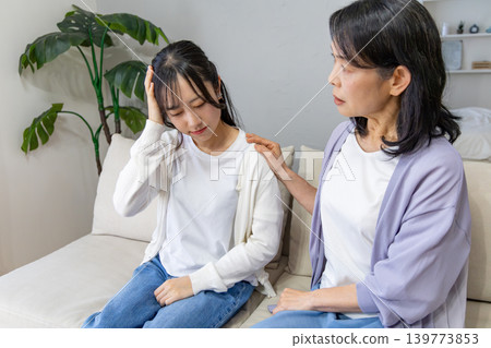 Daughter holding her head, mother worried. Daughter holding her head, mother worried. 139773853