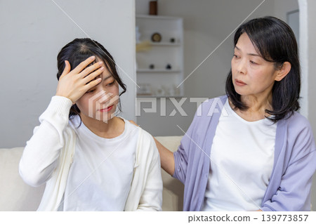 Daughter holding her head, mother worried. Daughter holding her head, mother worried. 139773857