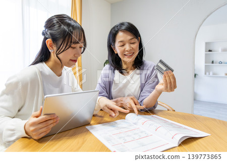 一對母女正在網路上瀏覽商品目錄。 一對母女正在網路上瀏覽商品目錄。 139773865