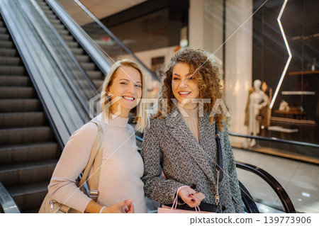 Two happy women shopping in the mall checking out stores 139773906