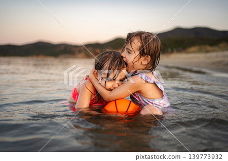 Sisters sharing a loving hug on a summer vacation Sisters sharing a loving hug on a summer vacation 139773932