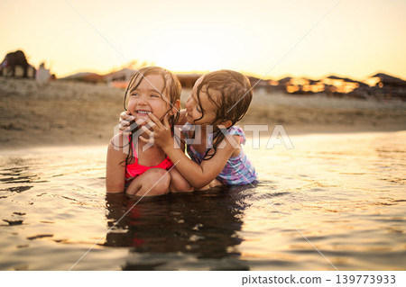Happy little sisters playing together enjoying summer beach vacation Happy little sisters playing together enjoying summer beach vacation 139773933