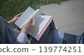 A close-up shot of a hand-held girl holding a pen and leafing through a notebook with handwritten notes. 139774251