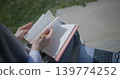 A close-up shot of a hand-held girl holding a pen and leafing through a notebook with handwritten notes. 139774252