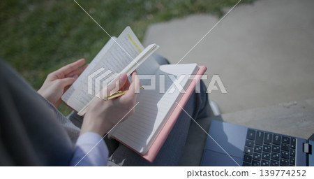 A close-up shot of a hand-held girl holding a pen and leafing through a notebook with handwritten notes. A close-up shot of a hand-held girl holding a pen and leafing through a notebook with handwritten notes. 139774252