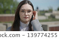 Close-up portrait of a young white female student wearing glasses with long dark hair in a park 139774255