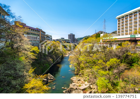 Nikko City, Tochigi Prefecture: The beautiful valley scenery and hotel complex of Kinugawa Onsen, under a clear blue sky and surrounded by lush greenery. 139774751