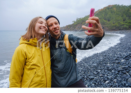 Couple taking selfie on beach in Winter Couple taking selfie on beach in Winter 139775154