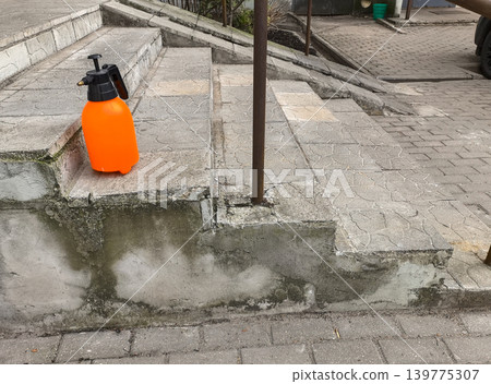 Orange plastic spray bottle on concrete stairs Orange plastic spray bottle on concrete stairs 139775307
