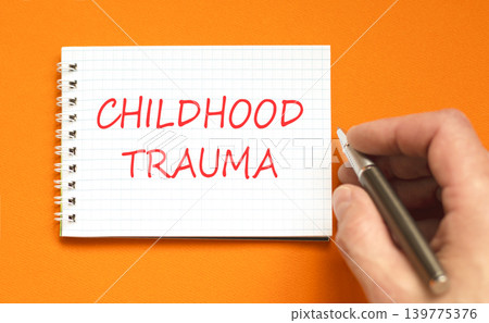 Childhood trauma words symbol. Concept words Childhood trauma on beautiful white note. Beautiful orange background. Psychologist hand. Psychological childhood trauma support concept. Copy space. Childhood trauma words symbol. Concept words Childhood trauma on beautiful white note. Beautiful orange background. Psychologist hand. Psychological childhood trauma support concept. Copy space. 139775376