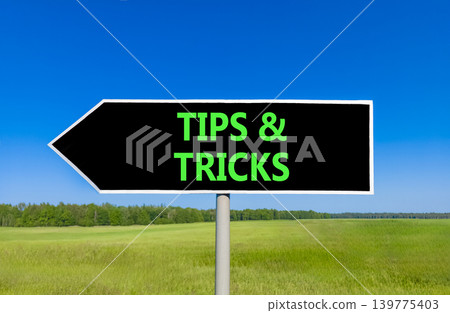 Tips and tricks words symbol. Concept words Tips and tricks on beautiful black road sign. Beautiful blue sky green field background. Business tips and tricks motivational support concept. Copy space. Tips and tricks words symbol. Concept words Tips and tricks on beautiful black road sign. Beautiful blue sky green field background. Business tips and tricks motivational support concept. Copy space. 139775403