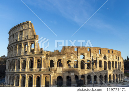 Famous Coliseum in Rome. Colosseum, or Coliseum. Sunset at huge Roman amphitheatre, Rome, Italy, Europe. Famous touristic place in the world and Europe. Beautiful blue sky background. Famous Coliseum in Rome. Colosseum, or Coliseum. Sunset at huge Roman amphitheatre, Rome, Italy, Europe. Famous touristic place in the world and Europe. Beautiful blue sky background. 139775471