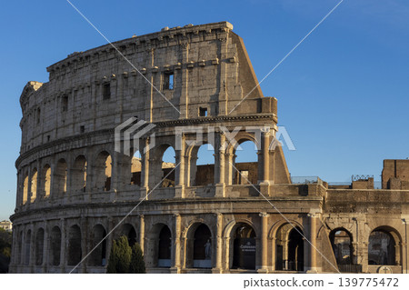 Famous Coliseum in Rome. Colosseum, or Coliseum. Sunset at huge Roman amphitheatre, Rome, Italy, Europe. Famous touristic place in the world and Europe. Beautiful blue sky background. Famous Coliseum in Rome. Colosseum, or Coliseum. Sunset at huge Roman amphitheatre, Rome, Italy, Europe. Famous touristic place in the world and Europe. Beautiful blue sky background. 139775472