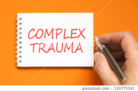 Complex trauma words symbol. Concept words Complex trauma on beautiful white note. Beautiful orange background. Psychologist hand. Psychological complex trauma support concept. Copy space. 139775591