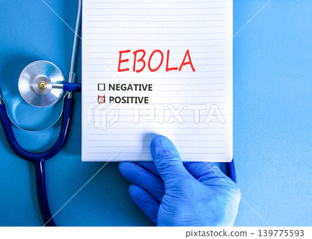 Ebola virus words symbol. Concept word Ebola positive on beautiful white note. Beautiful blue background. Doctor hand in blue medical glove. Stethoscope. Medical Ebola virus concept. Copy space. 139775593