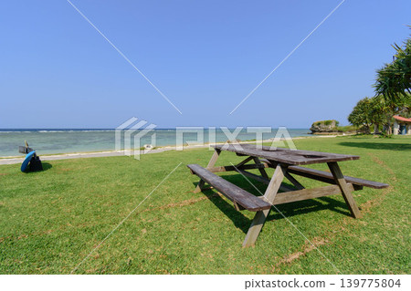 A beach with benches on a beautiful lawn and a vast blue sky. A beach with benches on a beautiful lawn and a vast blue sky. 139775804