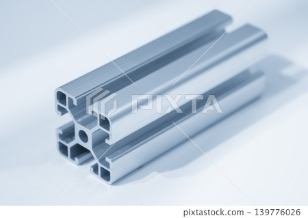 High-quality sample of an aluminum profile extrusion bar for industrial and structural applications in a blue-toned scene. High-quality sample of an aluminum profile extrusion bar for industrial and structural applications in a blue-toned scene. 139776026