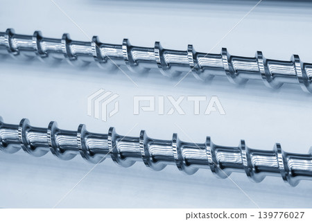 Close-up of a high-precision heavy-duty injection screw part for plastic molding machines in a blue-toned scene. Close-up of a high-precision heavy-duty injection screw part for plastic molding machines in a blue-toned scene. 139776027