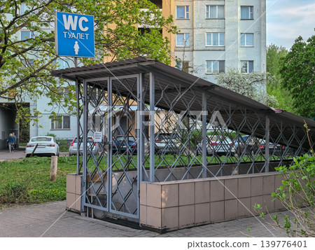 Closed public WC toilet with metal grate and blue sign in residential area Closed public WC toilet with metal grate and blue sign in residential area 139776401